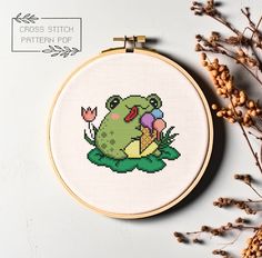 a cross stitch frog sitting on top of a flower