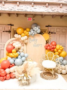 an outdoor display with balloons and chairs in front of the entrance to a baby's first birthday party