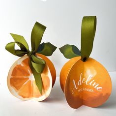 two oranges with green ribbons on them sitting next to each other in front of a white background