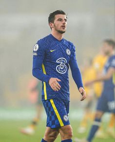 a man standing on top of a soccer field wearing a blue uniform and yellow socks