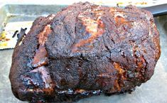 a large piece of meat sitting on top of a metal pan next to a knife