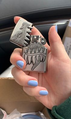 a woman's hand holding a lighter shaped like a shark with blue nail polish