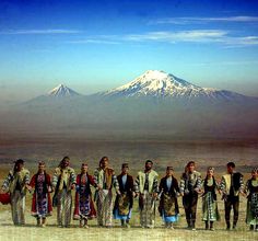 a group of people standing next to each other in front of a mountain with words written on it