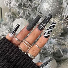 Bold matte black nails accented with silver snowflakes and candy cane stripes create a striking, modern Christmas look. Each nail offers a different winter-inspired design, from glittery snow to knitted textures, providing a unique and edgy holiday aesthetic. These nails are ideal for anyone looking to embrace a chic, non-traditional color scheme for the season. Art Noel, Christmas Tree Nails, Red Christmas Nails, Black Acrylic Nails, Tree Nails