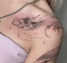 a woman's chest with a dragon tattoo on her left shoulder and the moon behind it