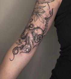 an octopus tattoo on the arm with vines and leaves around it's head is shown