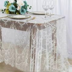 the table is set with white flowers and place settings for two people to sit at