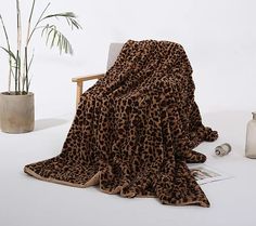 a leopard print blanket sitting on top of a chair next to a potted plant