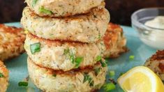 several crab cakes stacked on top of each other with lemon wedges next to them