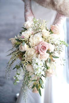 a bridal holding a bouquet of white and pink flowers in her hands with fur on the background