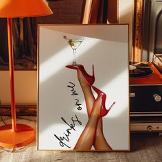 there is a framed photo with a woman's legs in high heels holding a martini