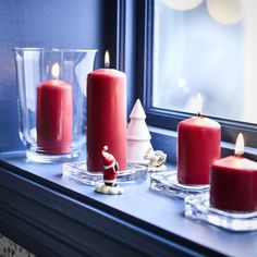 three red candles sitting on top of a window sill next to a christmas tree