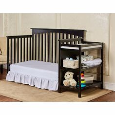 a baby crib that is next to a bed with a teddy bear on it