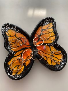 a butterfly shaped brooch with rings attached to it's back end, sitting on a white surface