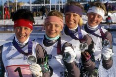 three women standing next to each other in the snow wearing headbands and gloves