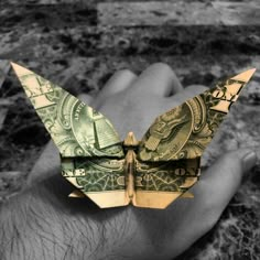 a hand holding an origami butterfly made out of money