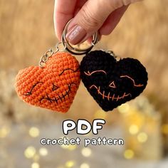 two crocheted pumpkins with faces on them are being held by a hand