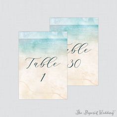 two wedding table numbers are shown in blue and green watercolors on white paper