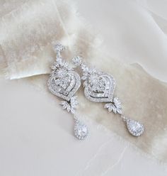 "Beautiful long statement earrings feature an Art Deco style with delicate details. Created with luxurious Swarovski Pure Brilliance stones set in a metal setting and embellished with a lovely crystal halo. Finished with Swarovski pearls. You can also choose a cz teardrop instead of pearls. Earrings measure 3\" x 1\" Available in 3 finishes Matching pieces: https://www.etsy.com/listing/475999054/rose-gold-bridal-bracelet-crystal https://www.etsy.com/listing/489501555/rose-gold-necklace-bridal-ne Opulent Silver Earrings For Wedding, Ornate Diamond-accent Earrings For Wedding, Diamond Chandelier Drop Earrings With Intricate Design, Diamond Chandelier Earrings With Intricate Design, Elegant Long Drop Chandelier Earrings With Sparkling Stones, Wedding Linear Earrings With Diamond Accents, Exquisite Silver Chandelier Drop Earrings, Wedding Long Drop Linear Earrings With Diamond Accents, Ornate Wedding Diamond Drop Earrings