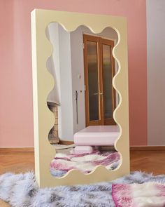 a mirror that is on the floor in front of a wall with a pink and white design