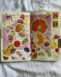 an open book with stickers on the pages and fruit cutouts attached to it