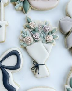 decorated cookies and cookie cutters on a white table with blue ribbons, roses, and bows