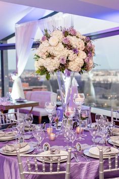 a vase filled with white and purple flowers sitting on top of a table covered in silverware