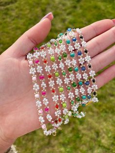 a hand holding a bunch of bracelets in it's left palm, with several different colored beads on them