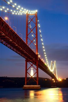 the golden gate bridge is lit up at night with lights on it's sides