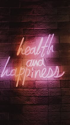 a neon sign that says health and happiness on a brick wall in front of it