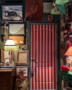 a room with pictures on the wall and a red striped door in front of it