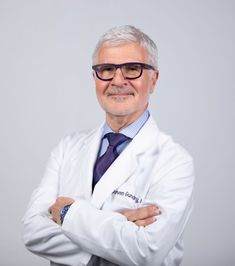 a man in a white lab coat and tie with his arms crossed looking at the camera