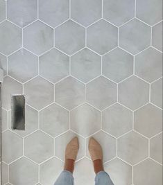 a person standing on a tiled floor with their feet up