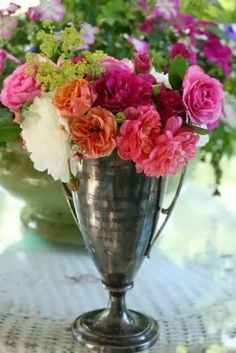 a silver vase filled with lots of colorful flowers