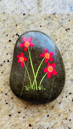 a rock with red flowers painted on it