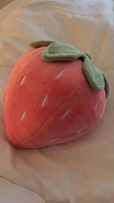 a pink strawberry pillow sitting on top of a bed