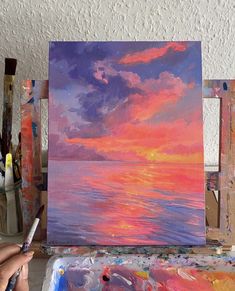 someone is painting a sunset over the ocean