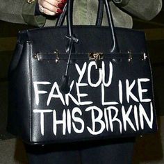 a woman holding a black purse with white writing on it that says you fake like this birkin