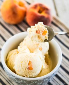 two scoops of ice cream in a bowl with peaches on the table behind it