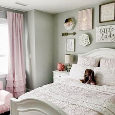 a white bed sitting in a bedroom next to a window with pink drapes on it