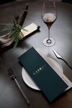 the table is set with silverware, wine glasses and menus for two people