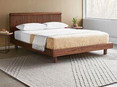 a bed sitting on top of a white rug next to a wooden headboard and foot board