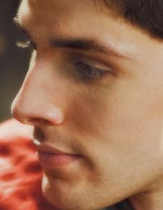 a close up of a young man wearing earring's and looking at his cell phone