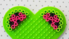 a green heart shaped brooch with pink and black beads on it's sides