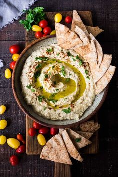 hummus in a bowl surrounded by corn, tomatoes, and tortilla chips