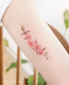 a woman's arm with pink flowers on the left side of her body,