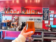 a woman holding up a drink in front of a bar