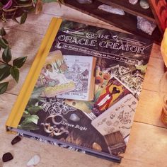 an open book sitting on top of a wooden table next to a vase with flowers