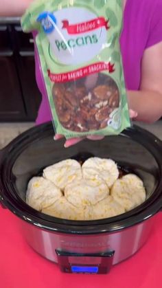 a person holding up a bag of food in an electric crock pot