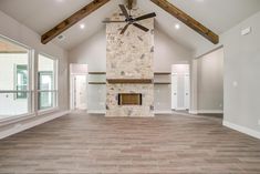 an empty living room with a stone fireplace and ceiling fan in the middle of it